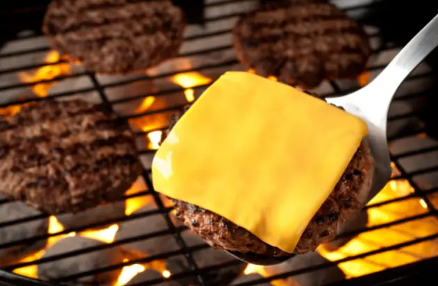 frozen patties on a grill grate with cheese