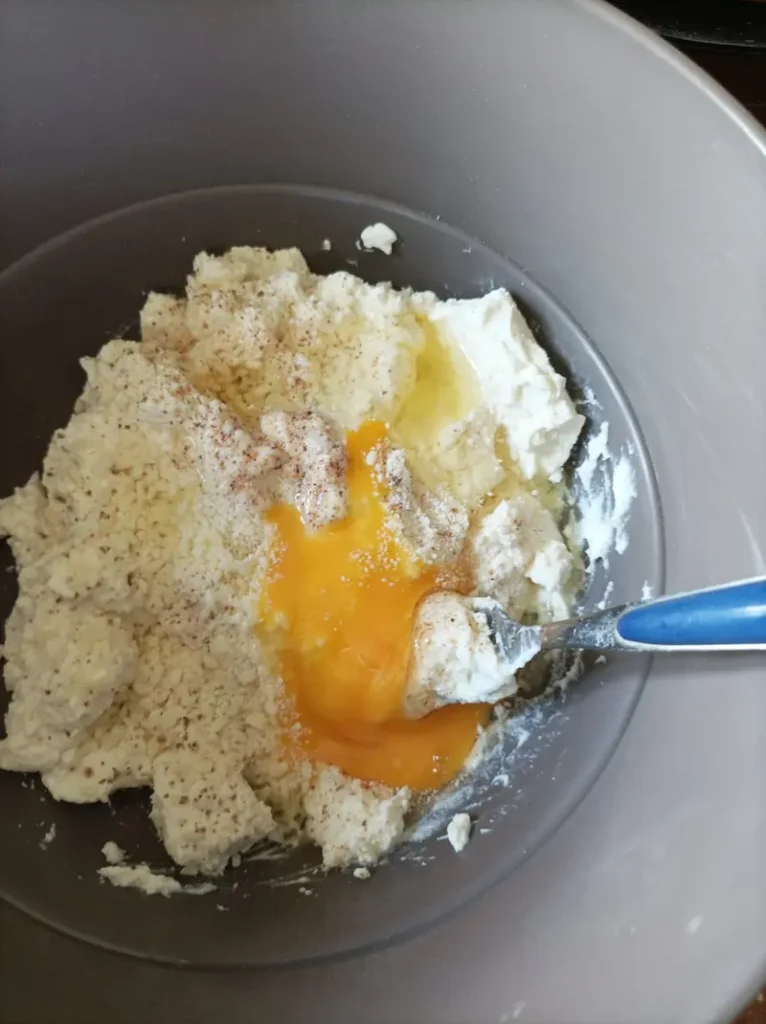 ricotta in a bowl with nutmeg, parmesan cheese and a beaten egg