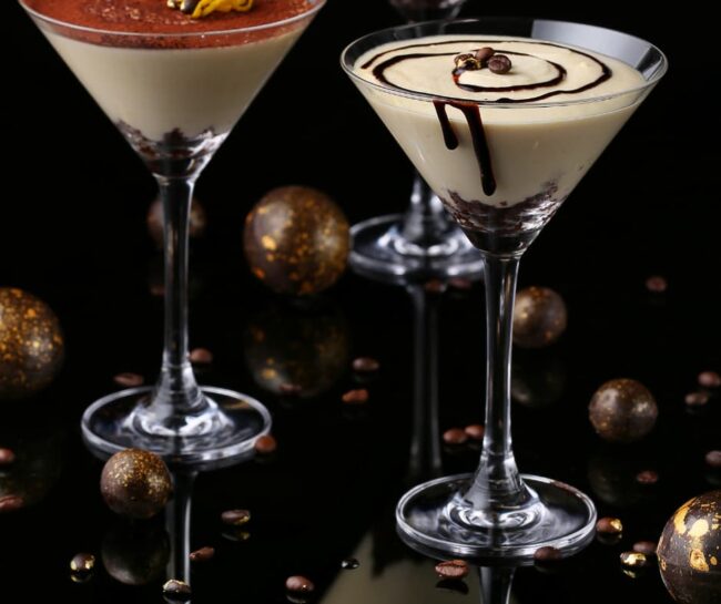detail of a tiramisu martini cocktail on a glass table in a dark environment