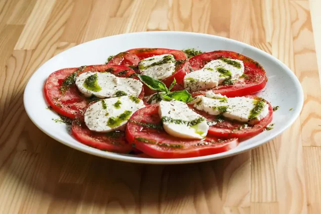 a caprese salad with pesto and ground black pepper