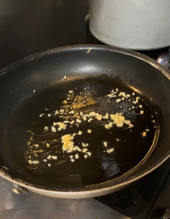 garlic browning in a pan - it's the first step of our pesto cream sauce recipe