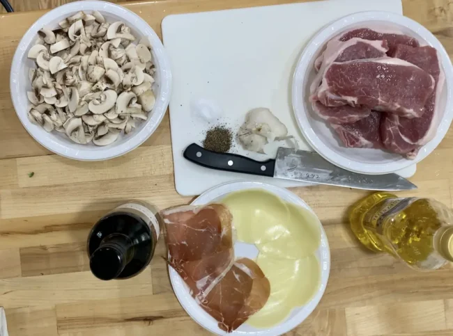 the ingredients needed for this gluten free pork chop recipe: mushrooms, cheese, prosciutto, olive oil, Marsala wine, garlic, butter and seasonings