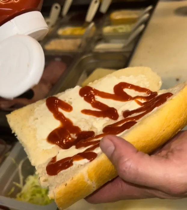 adding sauces to a hoagie roll