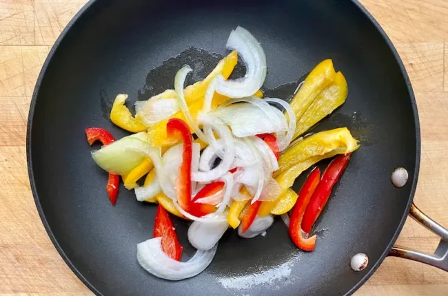sliced bell peppers and onions in a pan