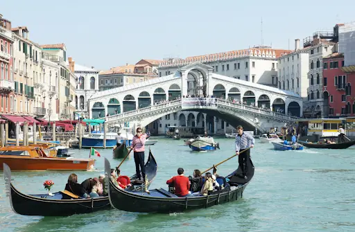 a gondola with tourists near the rialto bridge in venice