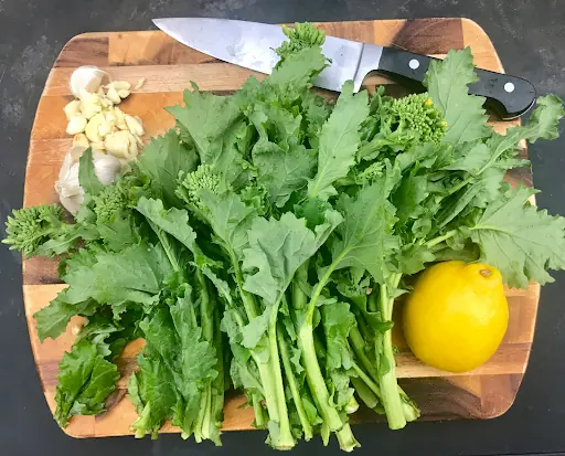 ingredients for sauteed rapini on a wooden surface