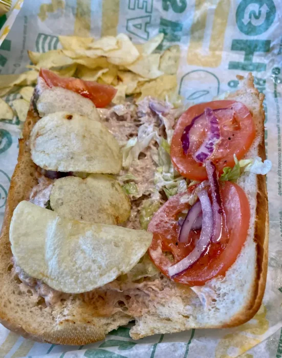 a subway tuna sandwich with chips