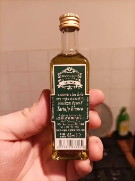 a hand holding a sample bottle of truffle oil