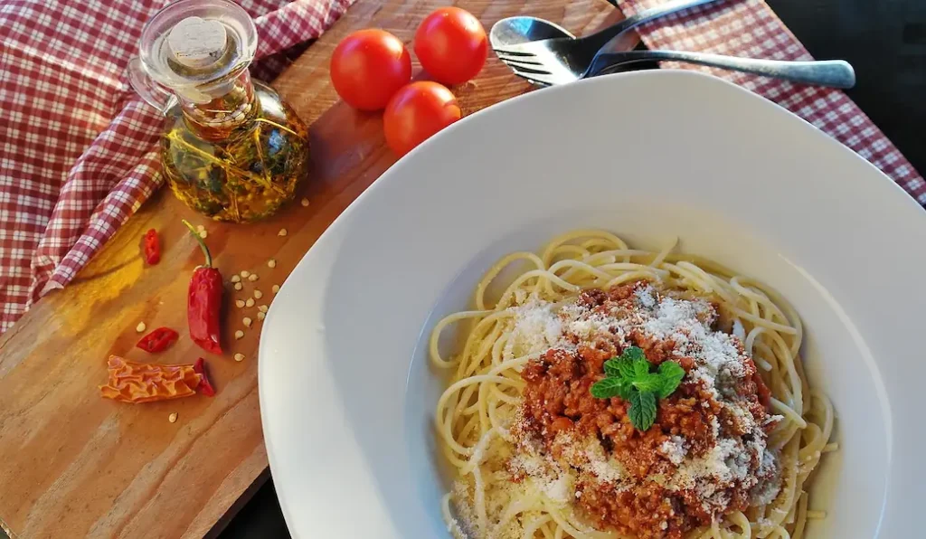 a bowl of pasta with a dried chili aside, showing one of the many wasy to use calabrian chili peppers in Italian cuisine