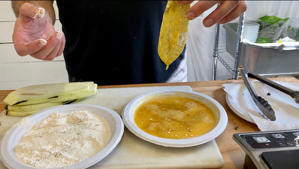 coating eggplant in flour and eggs for our eggplant parmigiana recipe