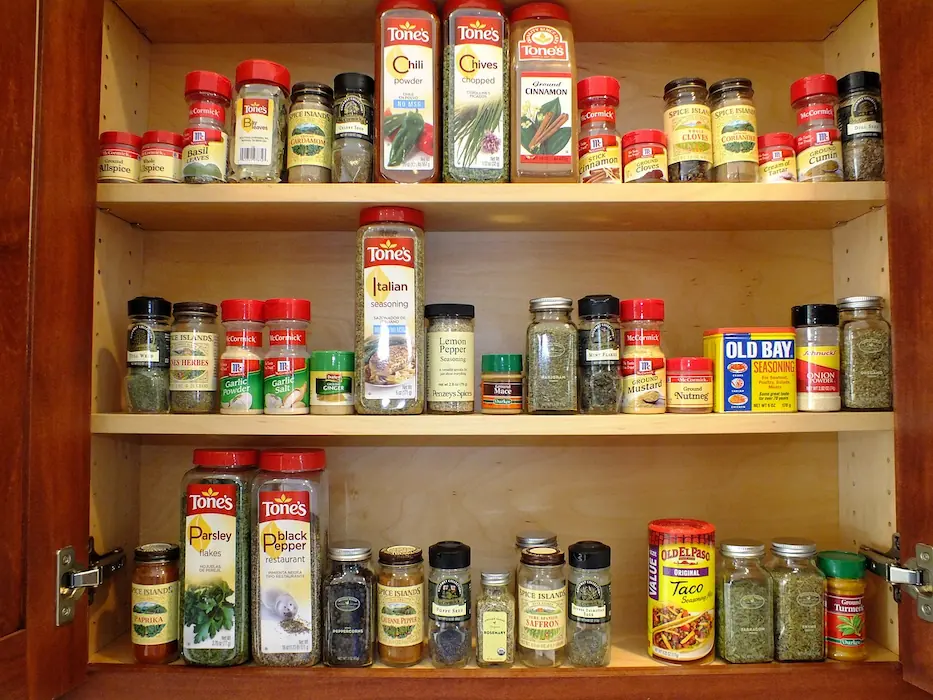 italian seasoning and other spices stored in a kitchen cabinet