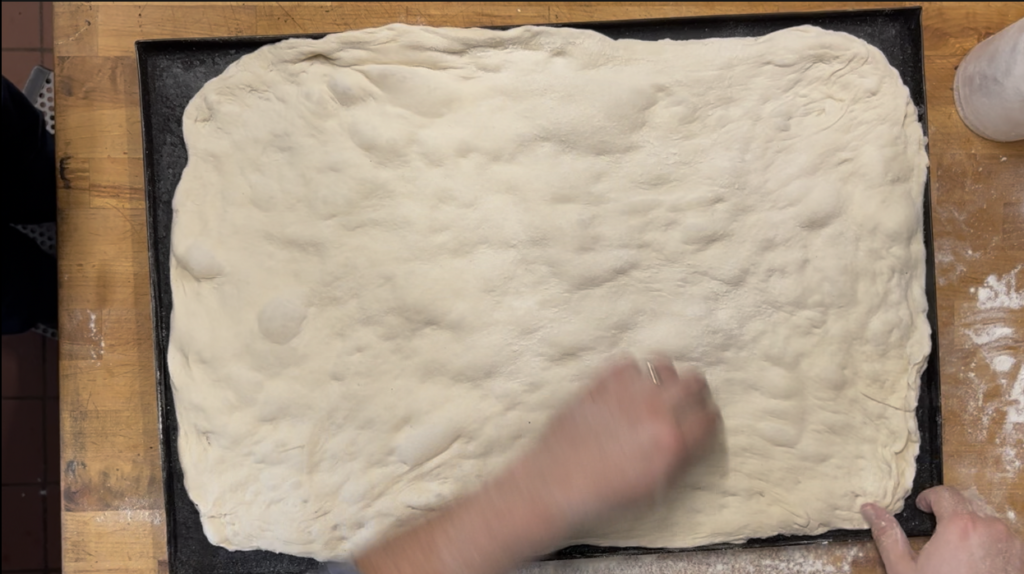 spreading the dough is one of the final steps of our roman pizza recipe