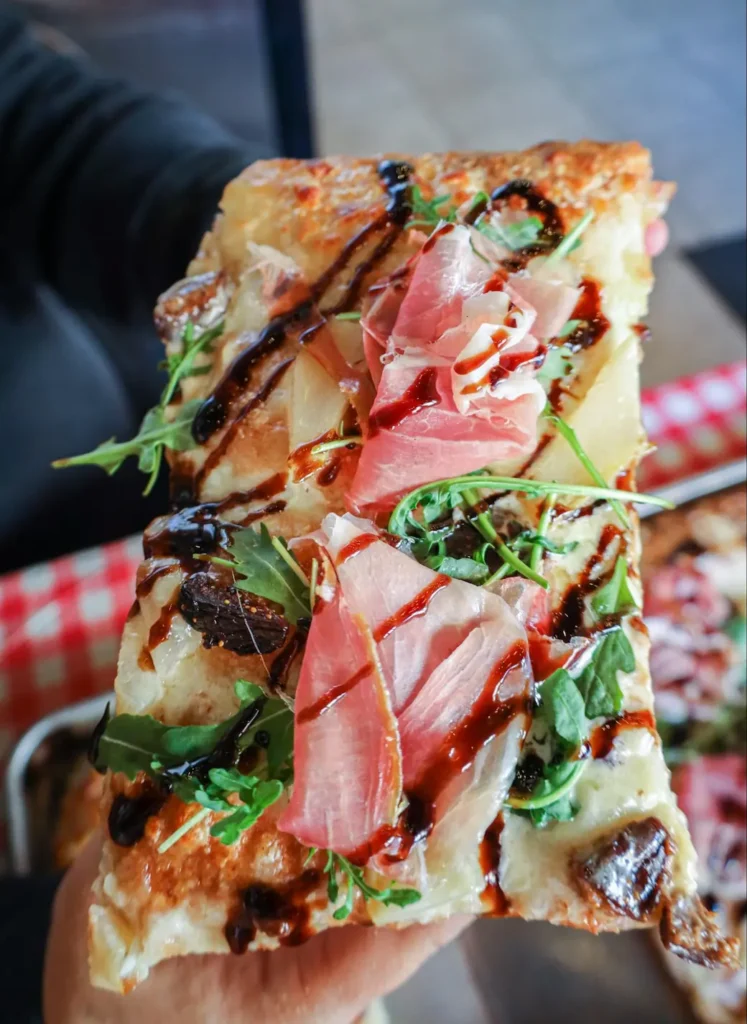 a slice of pear and prosciutto pizza made with this recipe