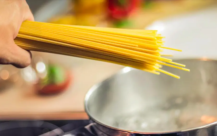 a hand about to put spaghetti in water