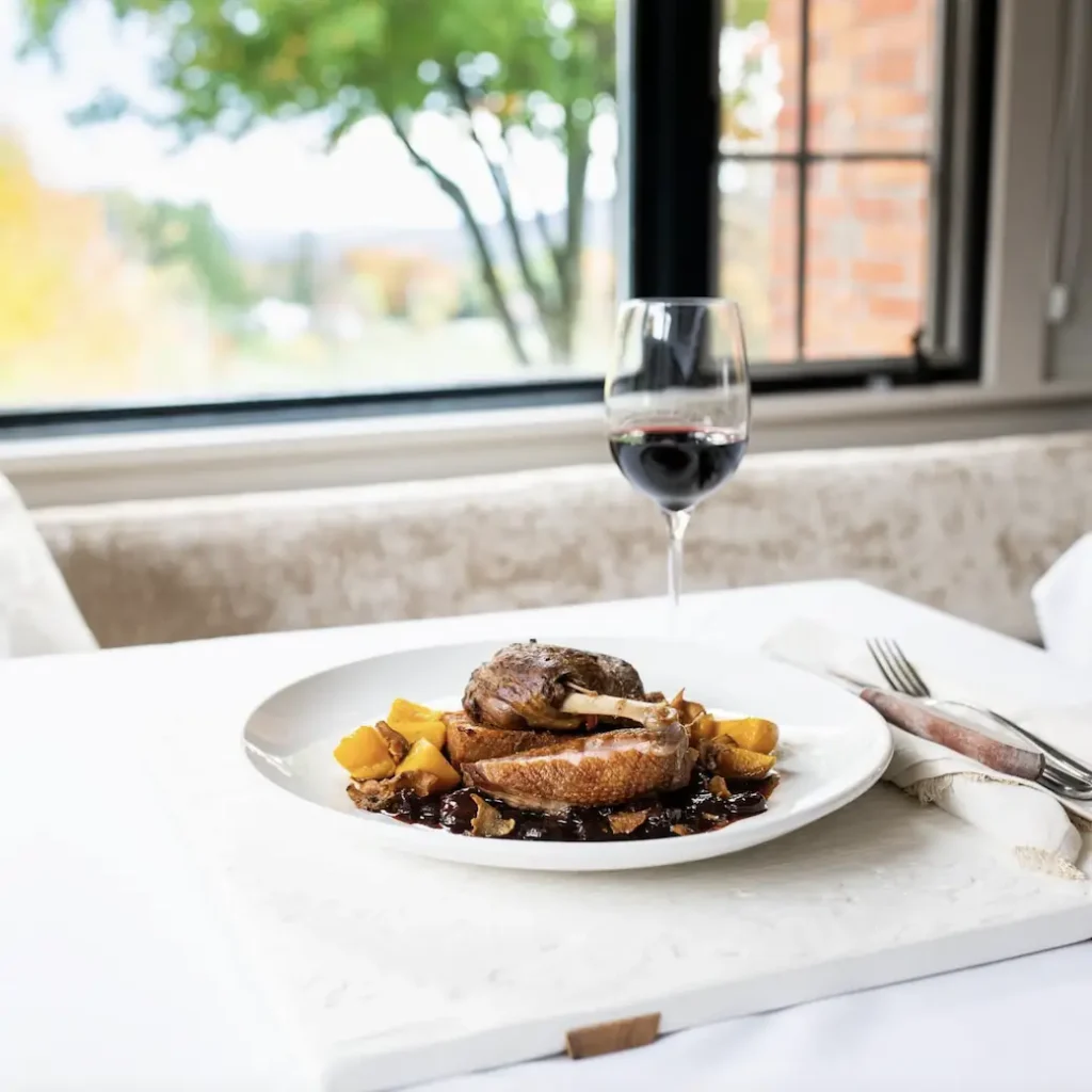 a plate of local food and a glass of wine from a table at Edson Hill restaurant in Stowe, Vermont