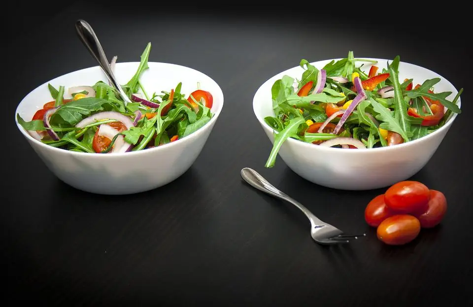 two bowls of arugula salad before being served with risotto
