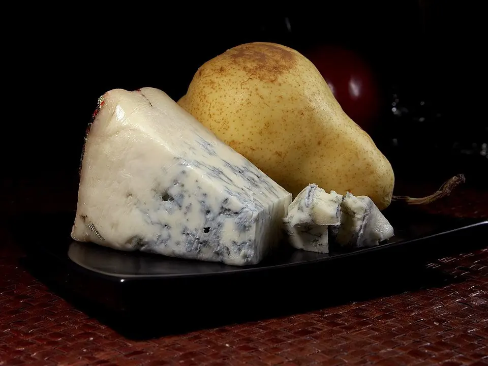 a piece of gorgonzola cheese placed next to a pear