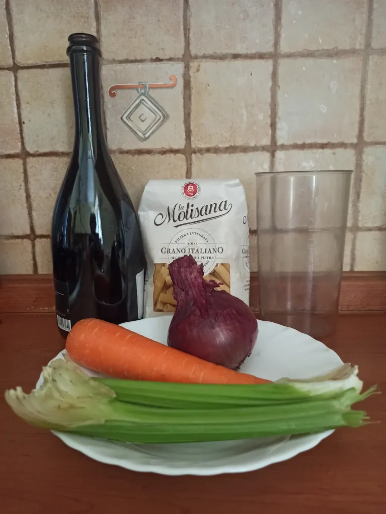 a picture of the ingredients: an onion, a carrot, two celery stalks, white wine, and pasta.