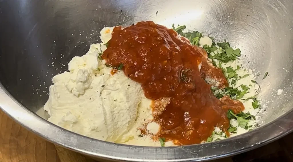 homemade ricotta being seasoned in a bowl