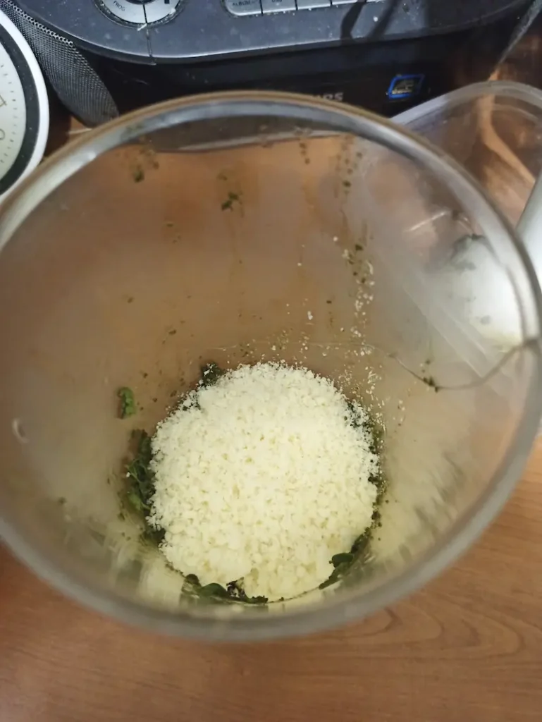parmesan cheese in an immersion blender, ready to be mixed with oregano pesto