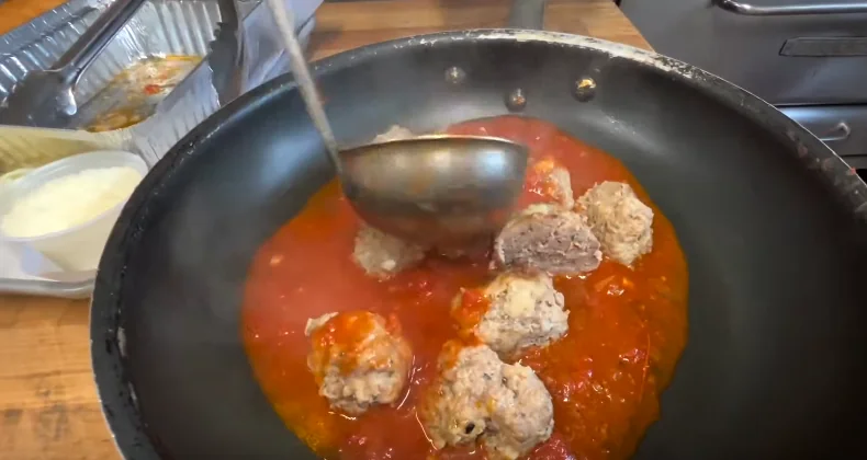 meatballs simmering with sauce in a saucepan to make a southern lasagna