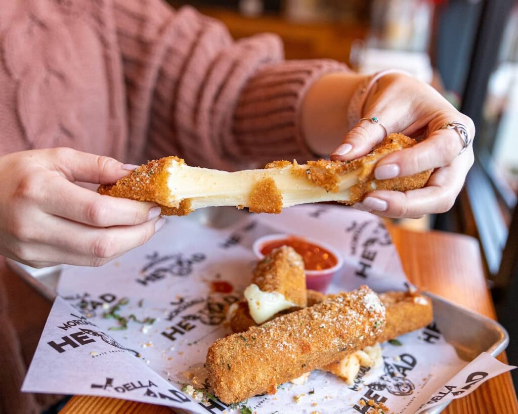 hands pulling a mozzarella stick reheated with an air fryer