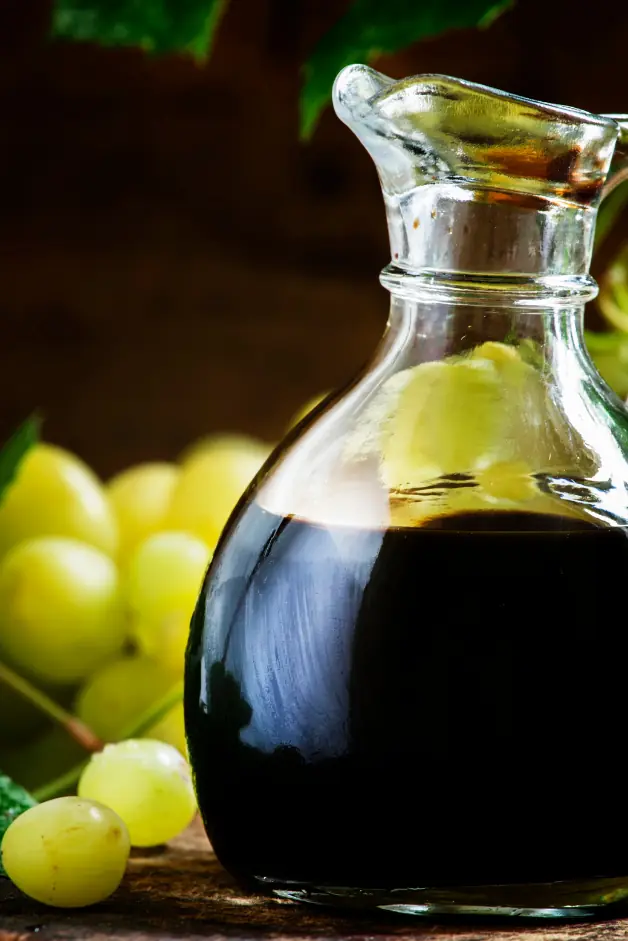 balsamic vinegar in a small glass carafe with some grapes in the background