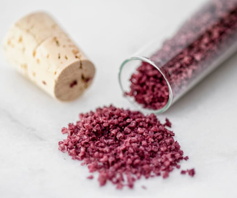 homemade red wine flavored coarse salt next to a little bottle and a cork