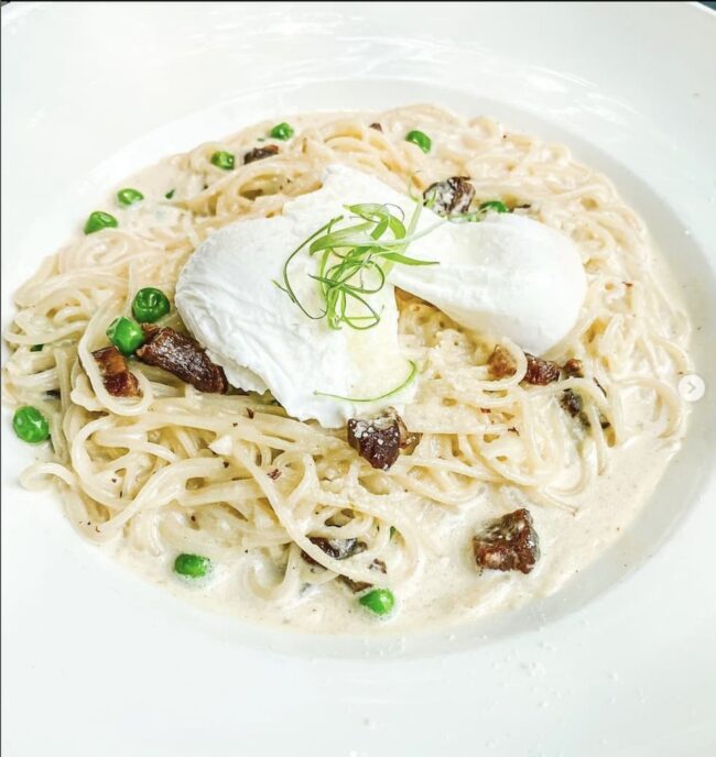 a plate of spaghetti with fresh herbs and mozzarella