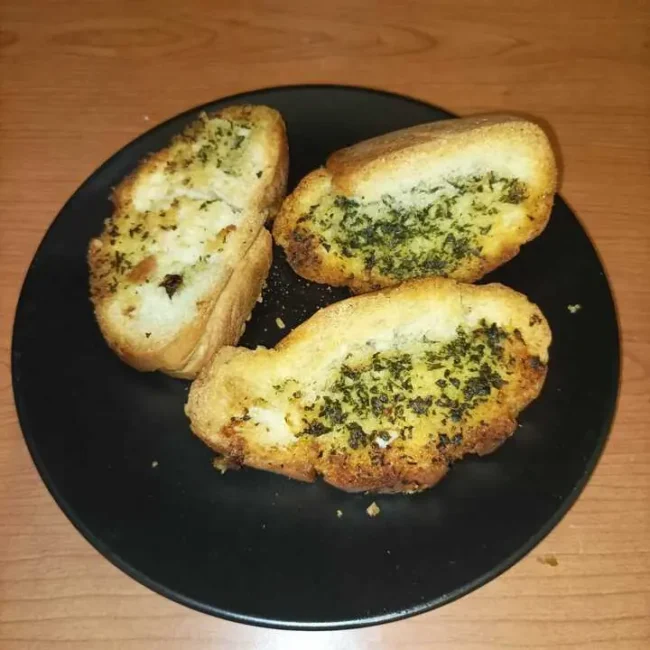three slices of ciabatta garlic bread on a black plate