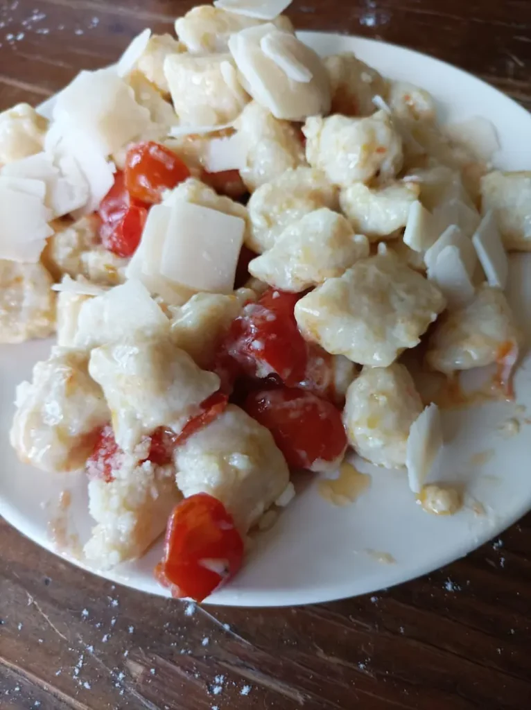 the ricotta gnocchi I just made with date tomatoes and parmesan flakes on a white plate