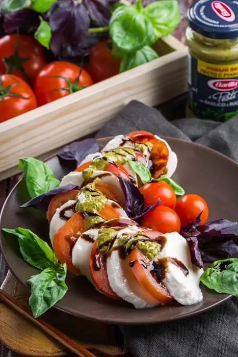 a caprese salad dressed with pesto and balsamic vinegar