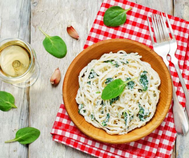 a bowl of ricotta pasta with spinach leaves