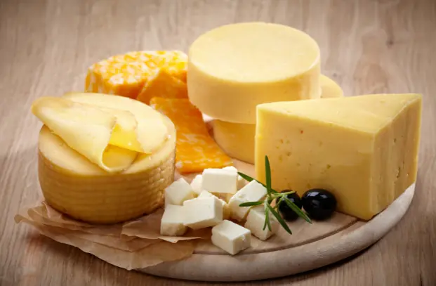 a bunch of cheeses on a wooden plate