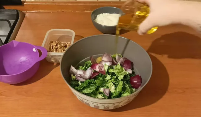 adding oil to onions and cabbage to make a cabbage pesto