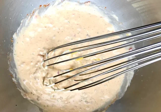 whisking spicy aioli / calabrian chili mayo in a bowl