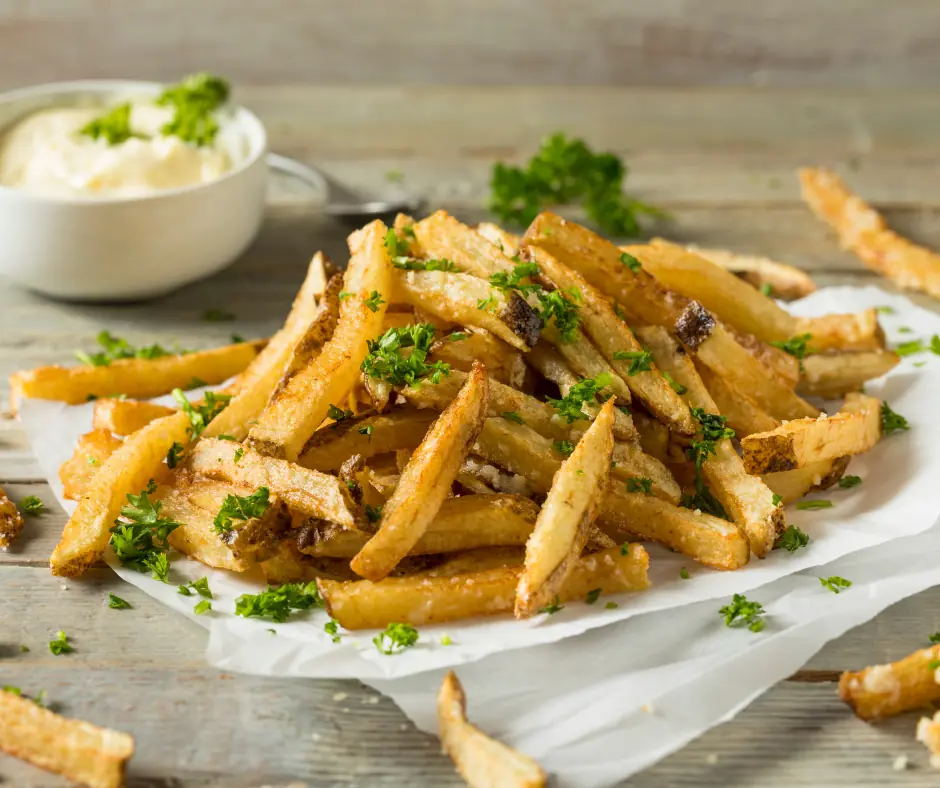 parmesan truffle fries on a paper towel near some dipping sauce