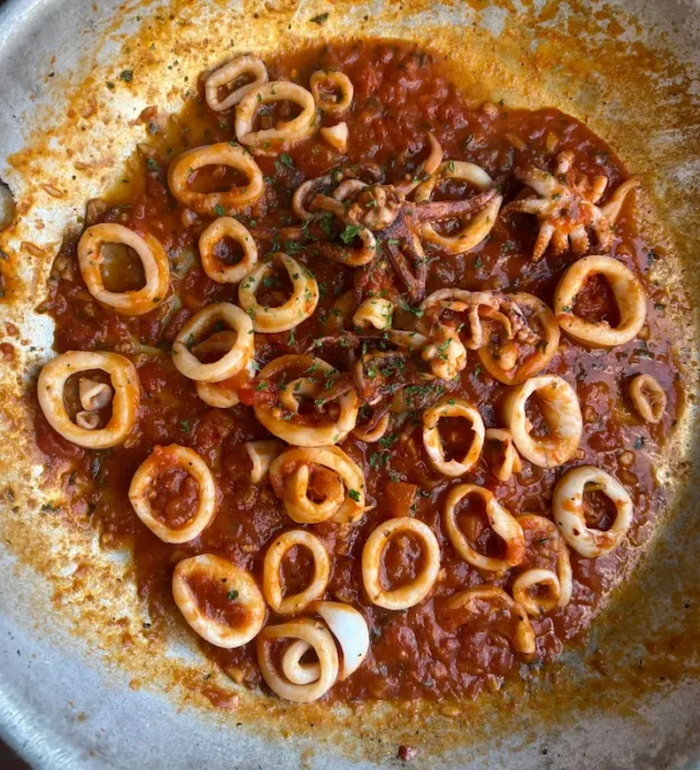 adding tomato sauce to sauteed calamari