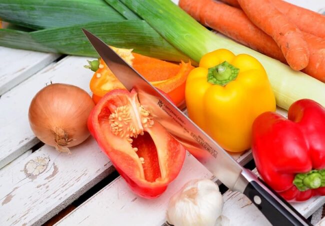 peppers and onions on a working surface with a knife and other vegetables