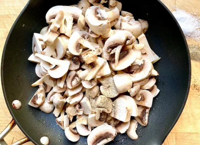 sauteeing mushrooms in a large pan