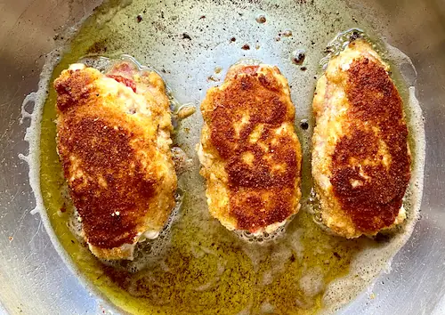 stuffed chicken rolls searing on the stove