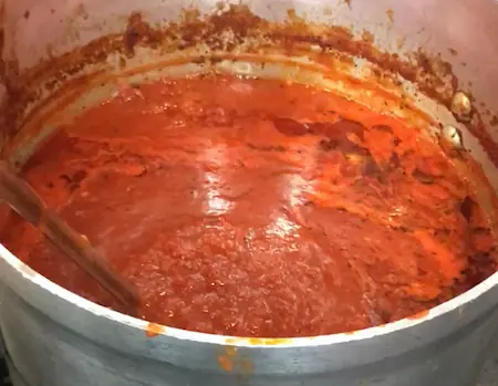 a large pot full with tomato sauce, ready to cook some meatballs on a stove