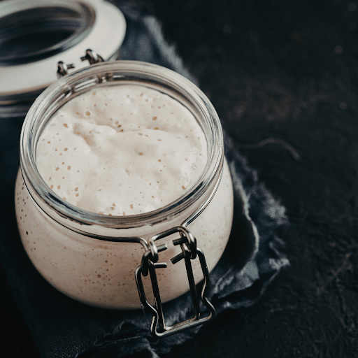 Glass jar filled with active sourdough starter on countertop