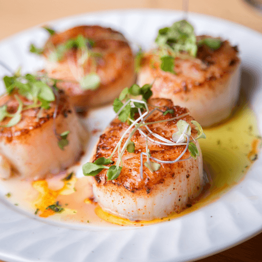 Seared scallops with golden crust and herb garnish on plate