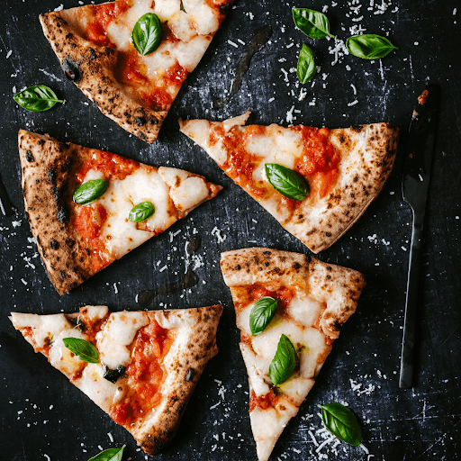 Sliced Margherita pizza arranged on a baking tray