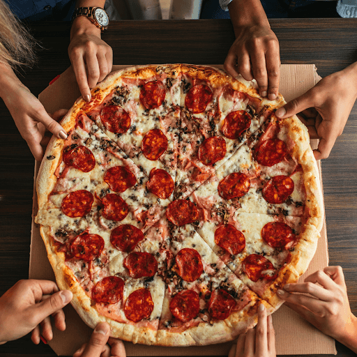 Whole pepperoni pizza being shared around the table